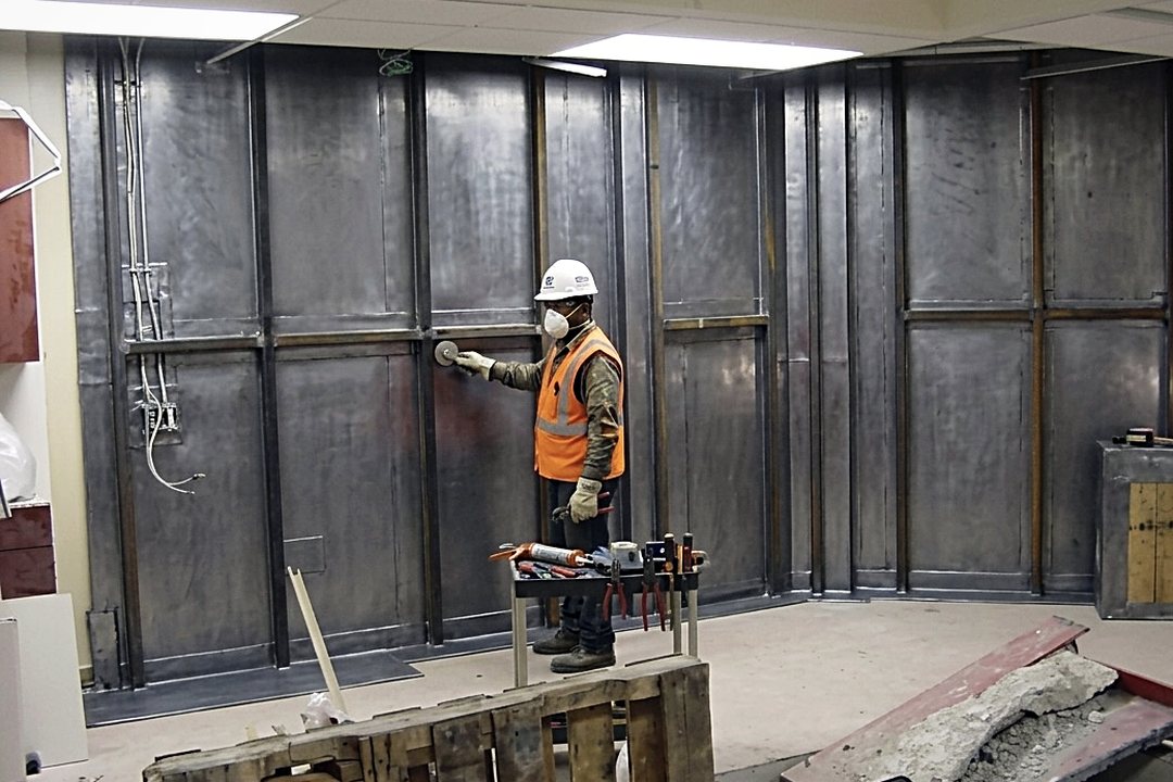 Technician installing lead sheet lining on the wall of a diagnostic imaging room